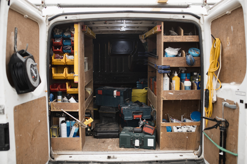 Interior view of a joiners van. There are tools and materials on shelves and boxes in the back of the van.